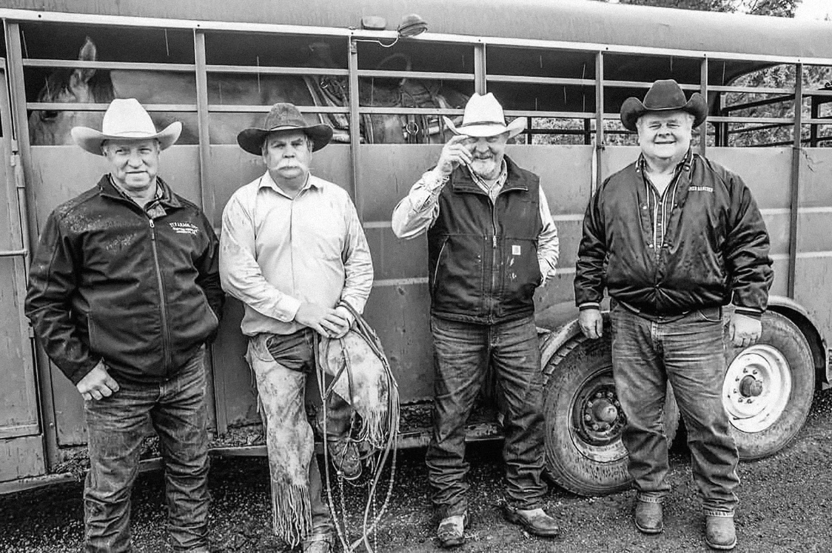 Four ranchers pose for camera against horse trailer; Mehrten Homer pictured to right